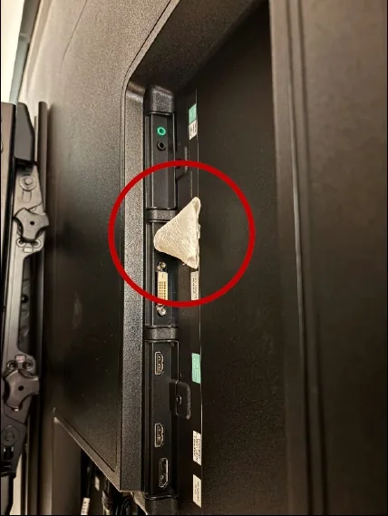 A small device wrapped in tissue, circled in red, plugged into the back of a television