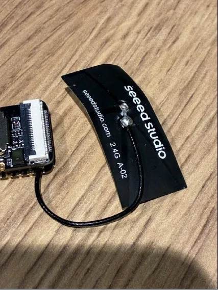 A small circuit board with a black antenna on a wooden table